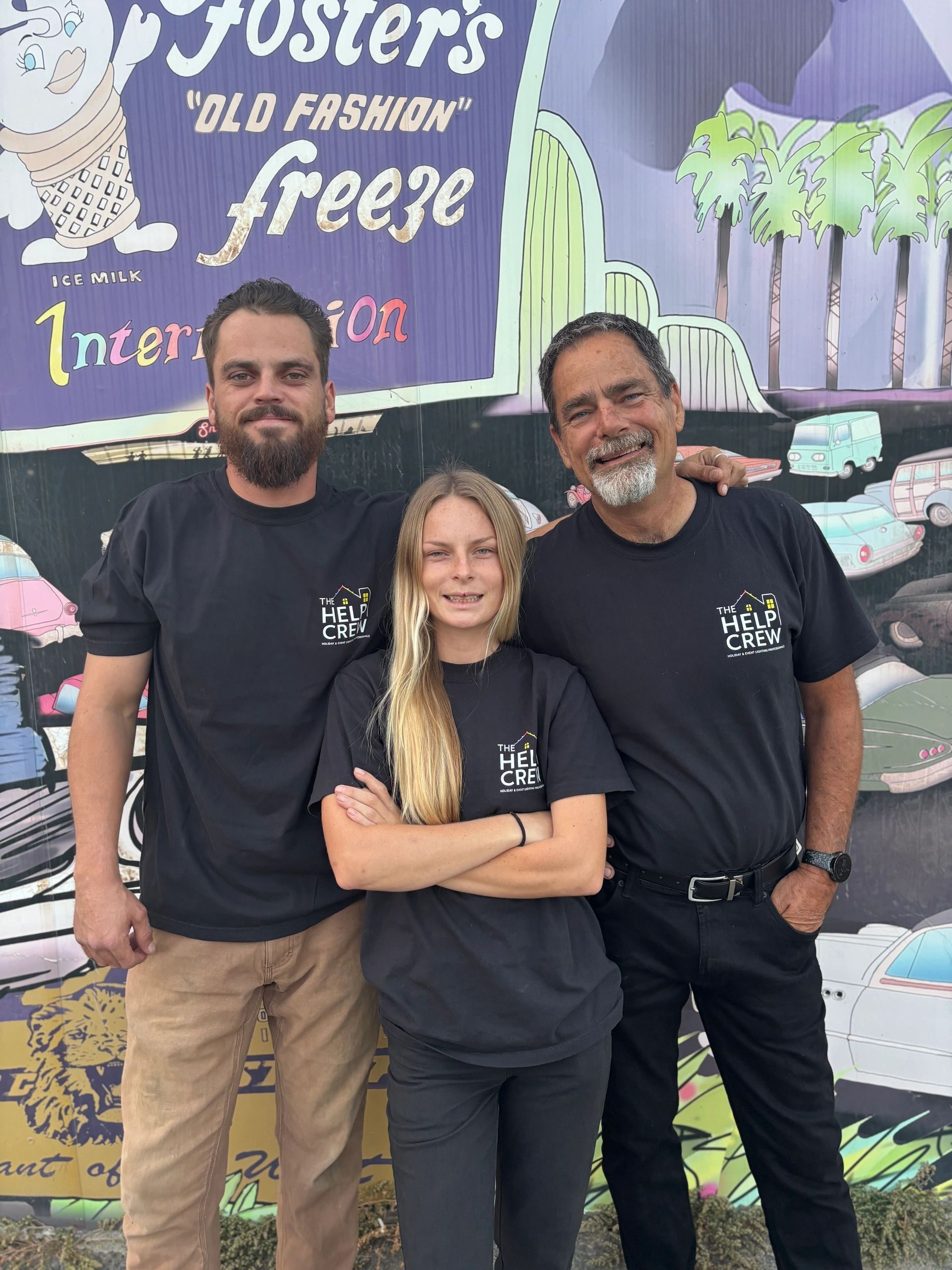 The Help Crew team in front of a colorful mural